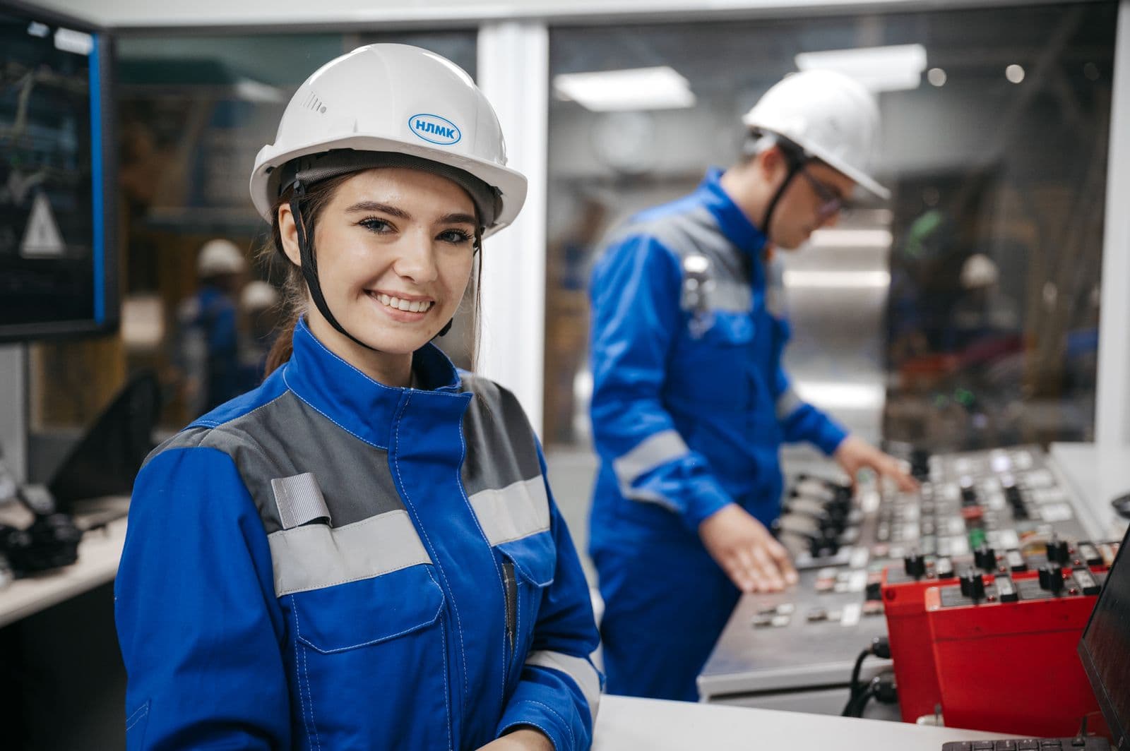 Angajată zâmbitoare în echipament de lucru și cască de protecție, într-o hală de producție